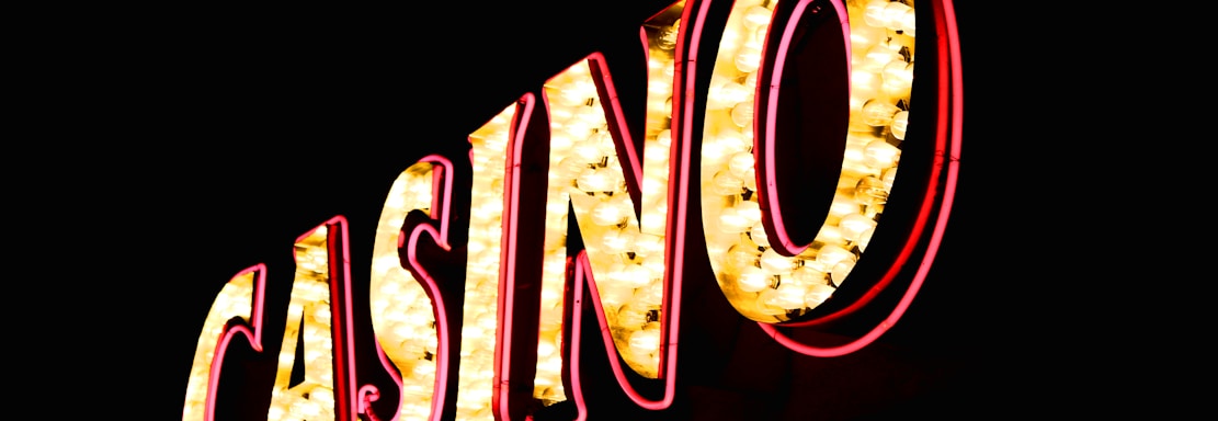 Brightly illuminated letters spell out 'CASINO' with glowing yellow bulbs and red outlines against a dark background.